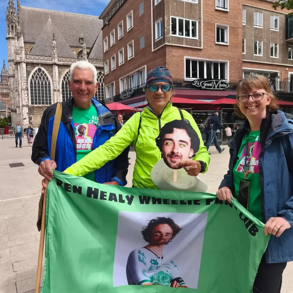 Ahmet Mumcu, the man who waves the Turkish flag at the Tour de France finished, with BEn Healey's parents during the Tour de France 2025