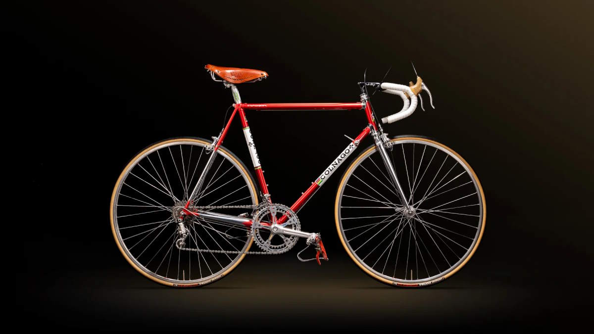 2026 Colnago Master steel road bike in Saronni red with chrome fork and classic components. Photographed against a dark background.