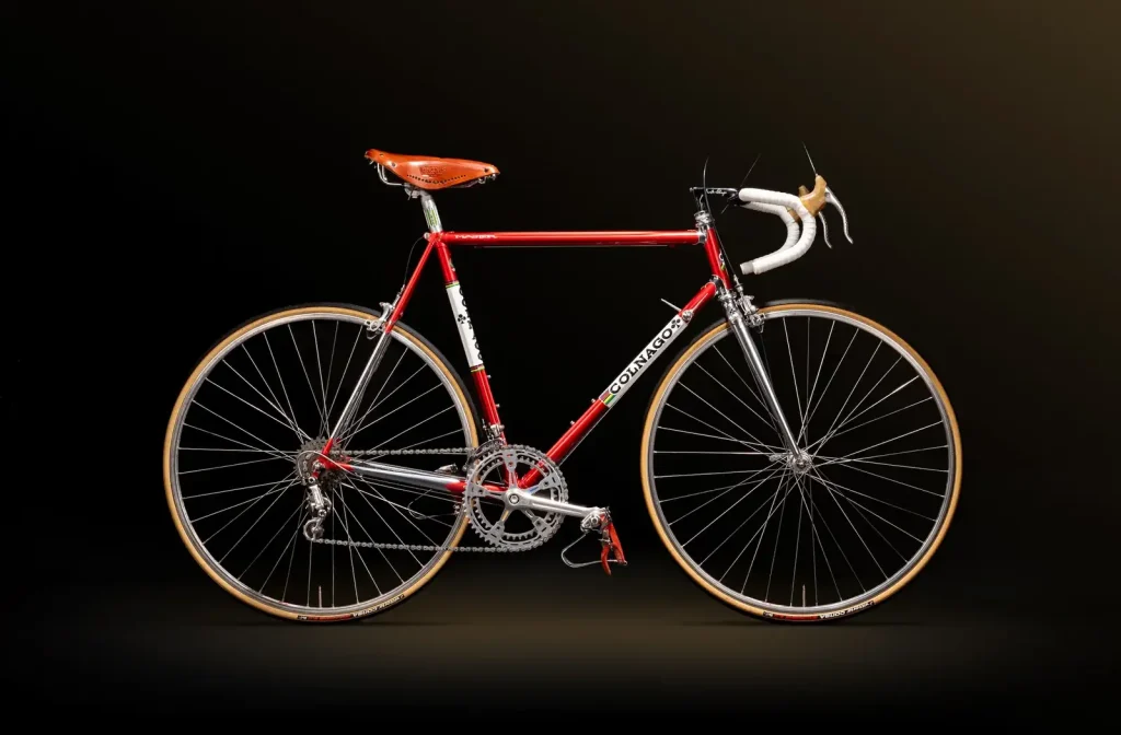 2026 Colnago Master steel road bike in Saronni red with chrome fork and classic components. Photographed against a dark background.